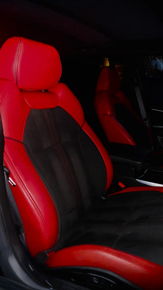 Freshly cleaned red and black leather bucket seats after an interior detail